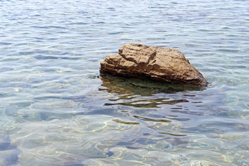 Solitary rock boulder in the sea water horizontal right