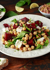 Healthy Beet Salad with chickpeas, pistachios nuts, feta and melted cheese toast on rustic wooden background