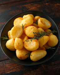 Roast golden potatoes seasoned with salt, garlic, rosemary and thyme on rustic wooden background