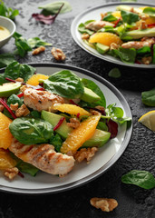 Grilled chicken with orange and avocado salad on rustic background