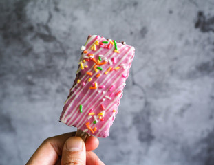 Ice cream covered in cracking strawberry milk with colorful sugar scab topping in hand. Sweet...