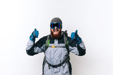 Excited bearded Hiker man showing thumbs up gesture with winter equipment ready for the trip in mountains