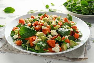 Avocado, roasted sweet potato, spinach, feta cheese healthy salad in white plate.