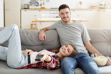 Young smiling couple watching tv on couch at home