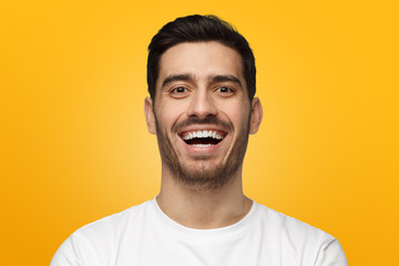 Close up portrait of handsome young man in white t-shirt laughing out loud