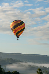 hot air balloon flying over english misty hills