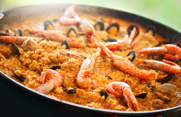 Paella. Traditional spanish food, seafood paella in the fry pan with mussels, king prawns, langoustine and squids. Cooking paella outside - obrazy, fototapety, plakaty