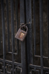 Conceptual picture of an old vintage rusty closed lock on rusty gate grill. Antique vintage rusty padlock on an abstract background. Antique rusty padlock closed lock. Big old lock closes this door