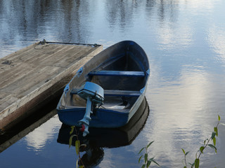 Old boat with an outboard motor moored at the pontoon