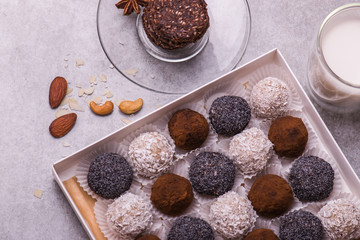 Chocolates with poppy seeds, coconut, nuts on a light background with a glass of milk.
