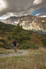 Fototapeta na wymiar Biker in the mountain, Mountain biker on the mountain pasture with mountains and blue sky as a background, traveling alone, on the corona time,