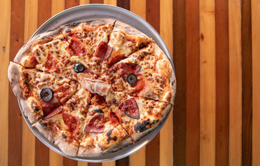 Gourmet Italian Meat Pizza on pizza stand and wooden table
