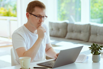 Handsome man works at home with his laptop