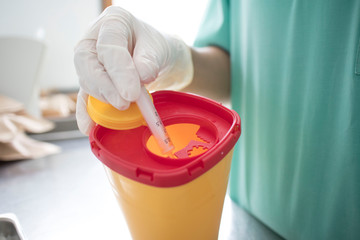 Doctor put syringe in red disposal boxes