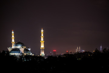Fototapeta na wymiar Night view of beautiful mosque with iconic landmark in the background 