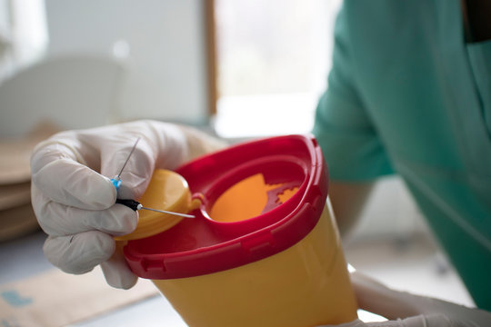 Doctor put syringe in red disposal boxes. concept of pandemic, coronavirus, virus, disinfection, panic.