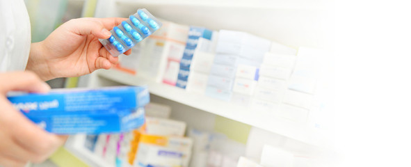 Pharmacist holding medicine box and capsule pack in pharmacy drugstore.copy space