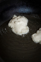 Cooking pancakes on a black pan with oil