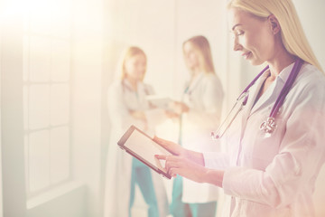 Fototapeta premium portrait of a young female doctor, with aipads in hand, in a medical office