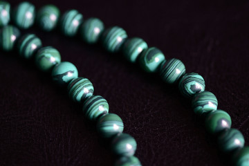 Malachite stone beads necklace on a dark background close up