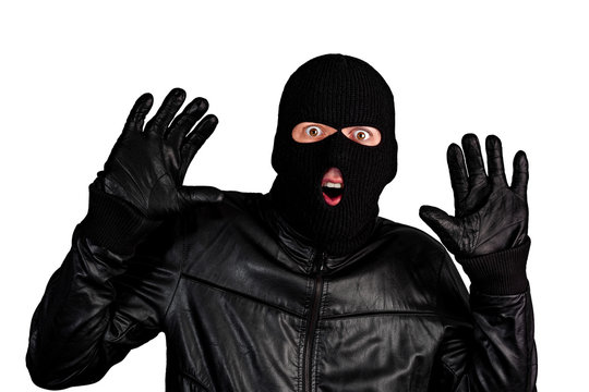 Arrested masked thief with raised arms isolated on white background