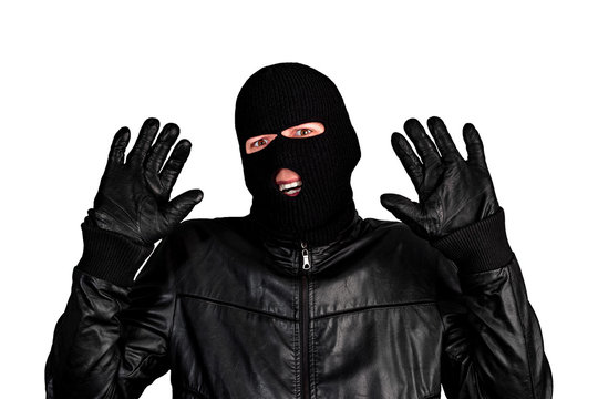Arrested masked thief with raised arms isolated on white background