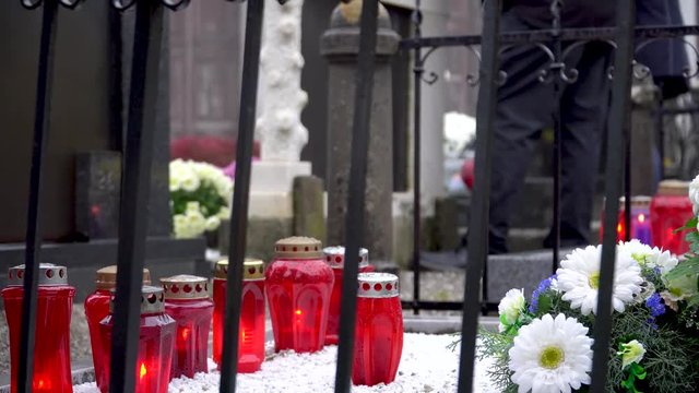 Candles on the graves with people standing by them