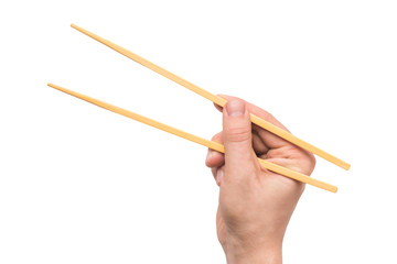 Person's right hand using bamboo chopsticks against white background