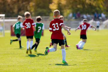 Boys kicking football on the sports field. An action sport picture of a group of kids playing...