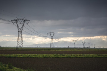 Electric pylons leading into a stormy sky, Italy