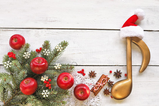 Christmas tree branch  with red apples,cinnamon, anise and music note on wooden  background 