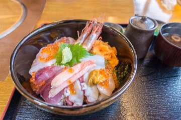 Premium fresh raw seafood mixed rice bowl , Japanese Rice with sashimi of tuna, Maguro, Otoro, salmon, squid and ikura (Salmon eggs) on wood background