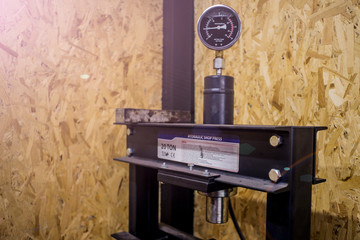 Hydraulic shop press with analog gauge and osb on background