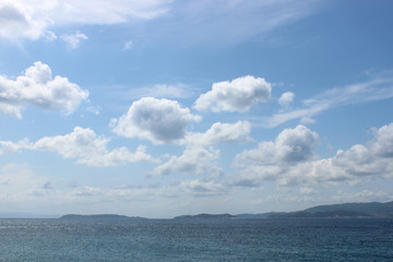 Distant shore landscape with sea, sky and puffy clouds