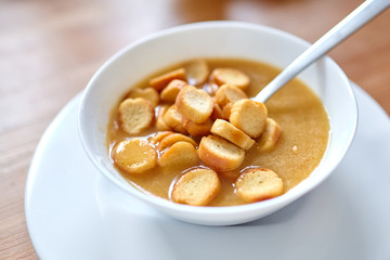 Vegetable soup with bread crumbs in a white bowl standing on a wooden table