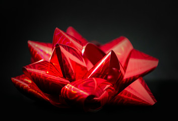 Large red bow on black background side view close up