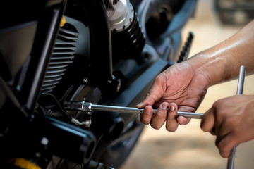 Image is Close up,People are repairing a motorcycle Use a wrench and a screwdriver to work.