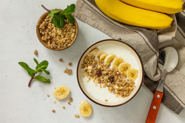 Granola. Granola with yogurt, chocolate and banana on a white stone table.