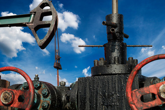 Low Angle View Of A Horsehead Pumpjack With Cloudy Blue Sky In Background / Low angle shot of a oil well pump against blue sky. oil and gas industry. Cloudy Blue Sky