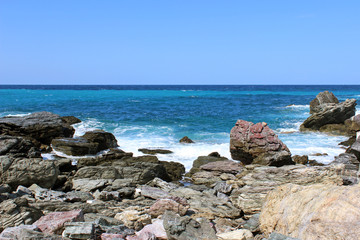Rocky sea water coastline with breaking waves with sea on horizon 