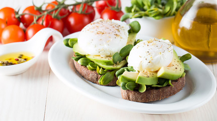 Fototapeta na wymiar Avocado toast, cherry tomato on wooden background. Breakfast with toast avocado, vegetarian food, healthy diet concept. Healthy sandwich with avocado and poached eggs.