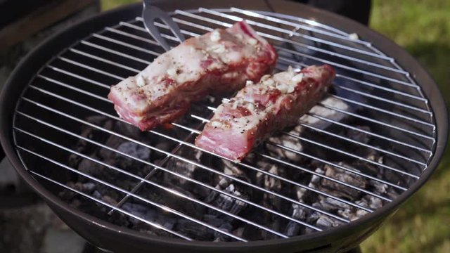 cook lays raw ribs on barbecue grill