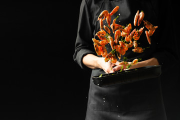 Professional chef prepares shrimps with greens. Cooking seafood, healthy vegetarian food, and food...
