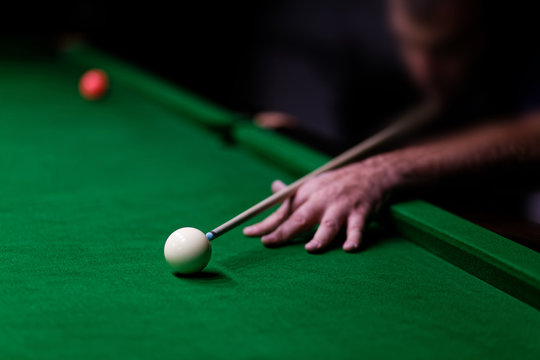 Man trying to hit the ball in billiard. Shallow focus.
