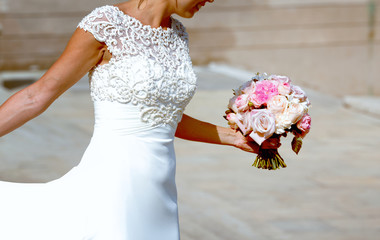 Woman is holding beautiful wedding bouquet in her hands.