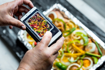 The person is photographing a food with a smartphone