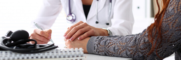 Friendly female doctor hold patient hand in office
