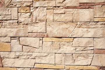 Background from a decorative tile of natural color. External decoration of the facade of the building with flesh-colored stone tiles.