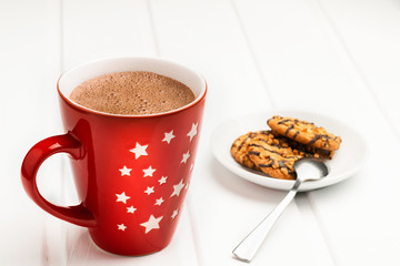 Hot cocoa in a red mug and saucer with cookies.