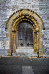 Interesting doorway found in Plymouth, England with a colorful stone frame and weathered wood and black iron door